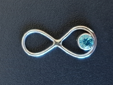 zu sehen ist ein Kettenanhänger in Silber 935 in der Form eines hängenden Endloszeichens. In der unteren Schleife ist ein Zirkon in Aquamarinfarbe eingearbeitet
