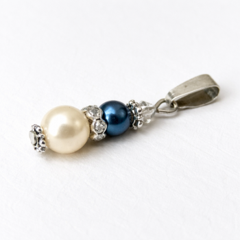 Unser Kettenanhänger Perltropfen ist aus zwei Wachsperlen, Edelstahlperlkappen und einem Strassrondell gefertigt. Abgerundet wir der Anhänger am oberen Ende mit einer Swarovski Raute. Der Anhänger ist durch Handarbeit bei uns in Abenberg hergestellt.