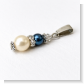 Unser Kettenanhänger Perltropfen ist aus zwei Wachsperlen, Edelstahlperlkappen und einem Strassrondell gefertigt. Abgerundet wir der Anhänger am oberen Ende mit einer Swarovski Raute. Der Anhänger ist durch Handarbeit bei uns in Abenberg hergestellt.